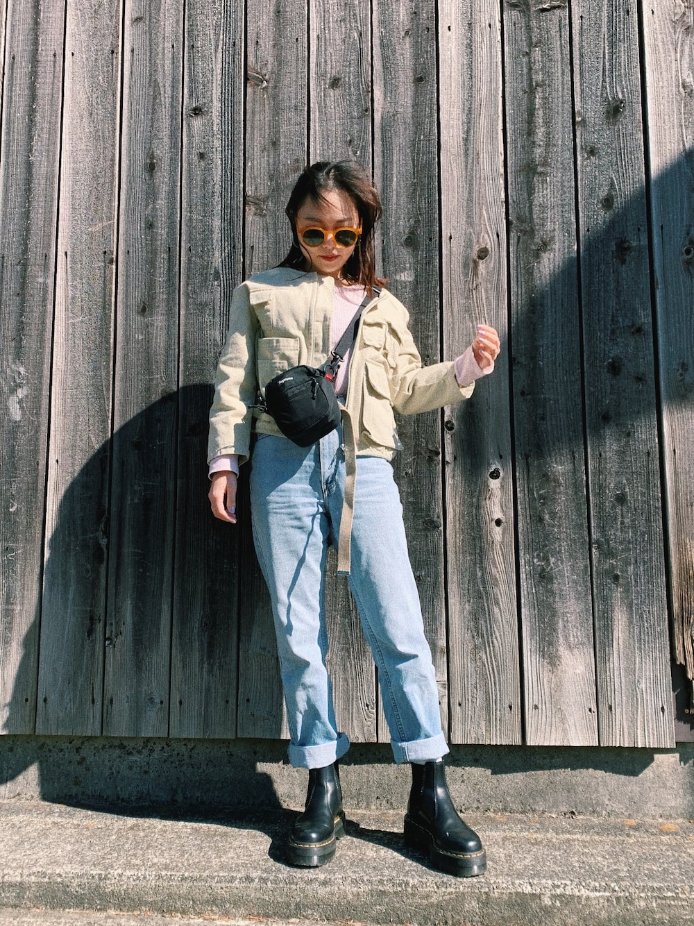 ピンク系のTシャツ/カットソー、ブラック系のボディバッグ/ウエストポーチ、ブルー系のデニムパンツを着用したレディースの春コーディネートの1枚目の写真