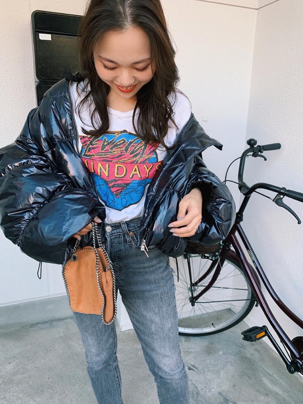 ブラック系のダウンジャケット/コート、ホワイト系のTシャツ/カットソー、ブラウン系のバッグを着用したレディースの秋コーディネートの1枚目の写真