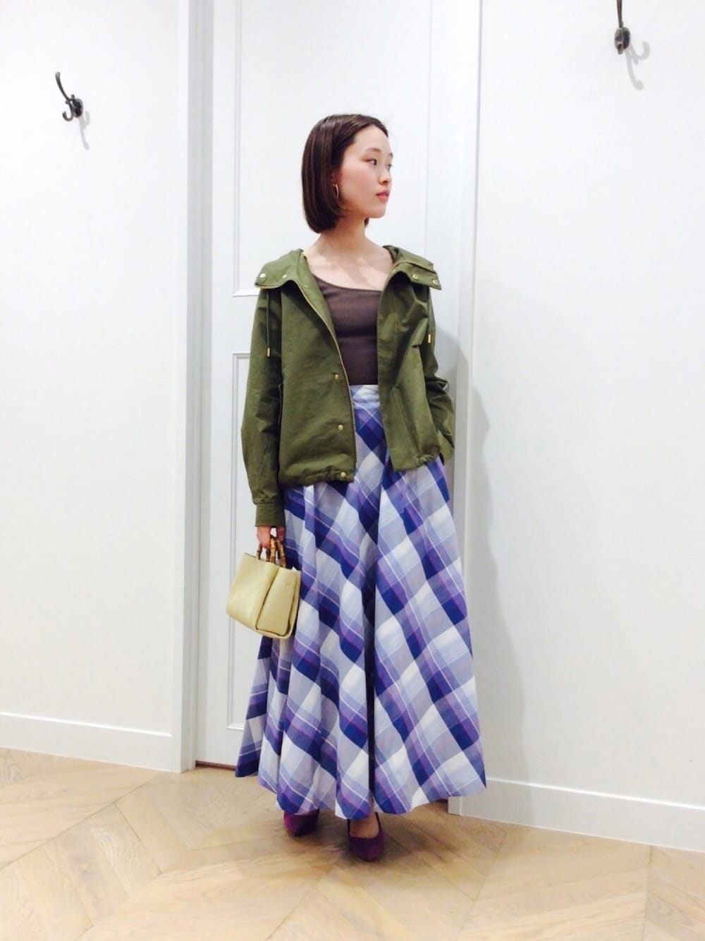 グリーン系のブルゾン、ブルー系のスカート、ベージュ系のショルダーバッグを着用したレディースの春コーディネートの1枚目の写真