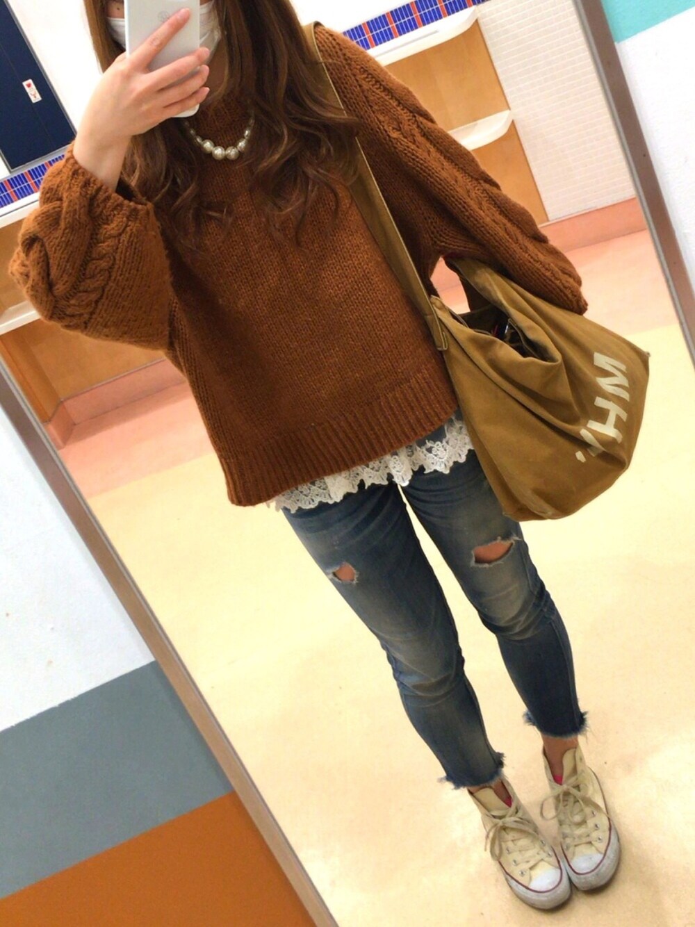 ブラウン系のショルダーバッグ、ブルー系のデニムパンツ、ホワイト系のスニーカーを着用したレディースの春コーディネートの1枚目の写真