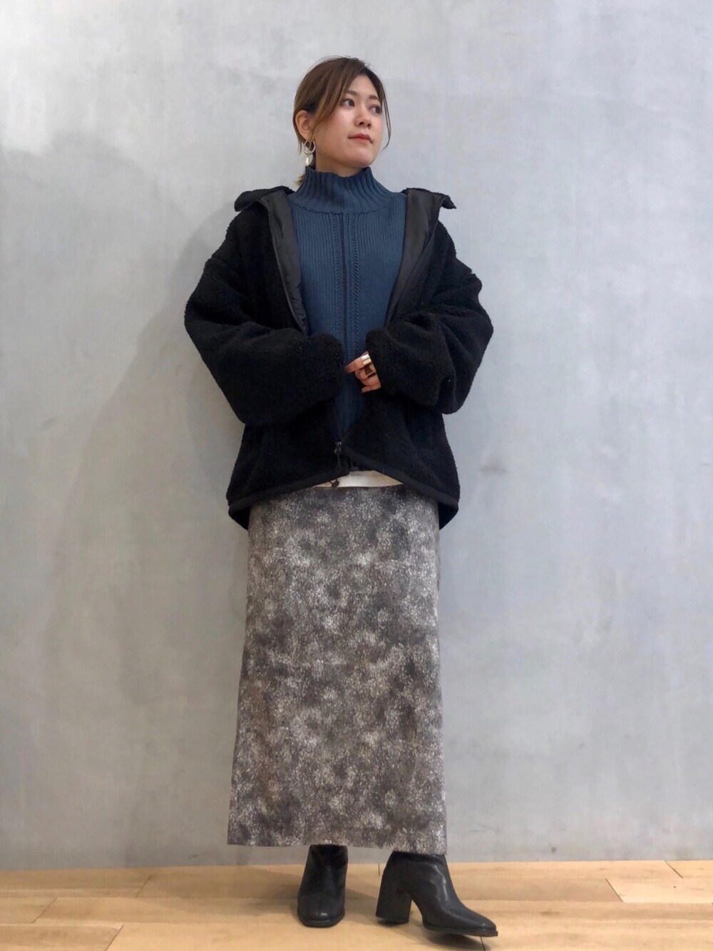 ブルー系のニット/セーター、ホワイト系のTシャツ/カットソー、ブラック系のその他アウターを着用したレディースの冬コーディネートの1枚目の写真