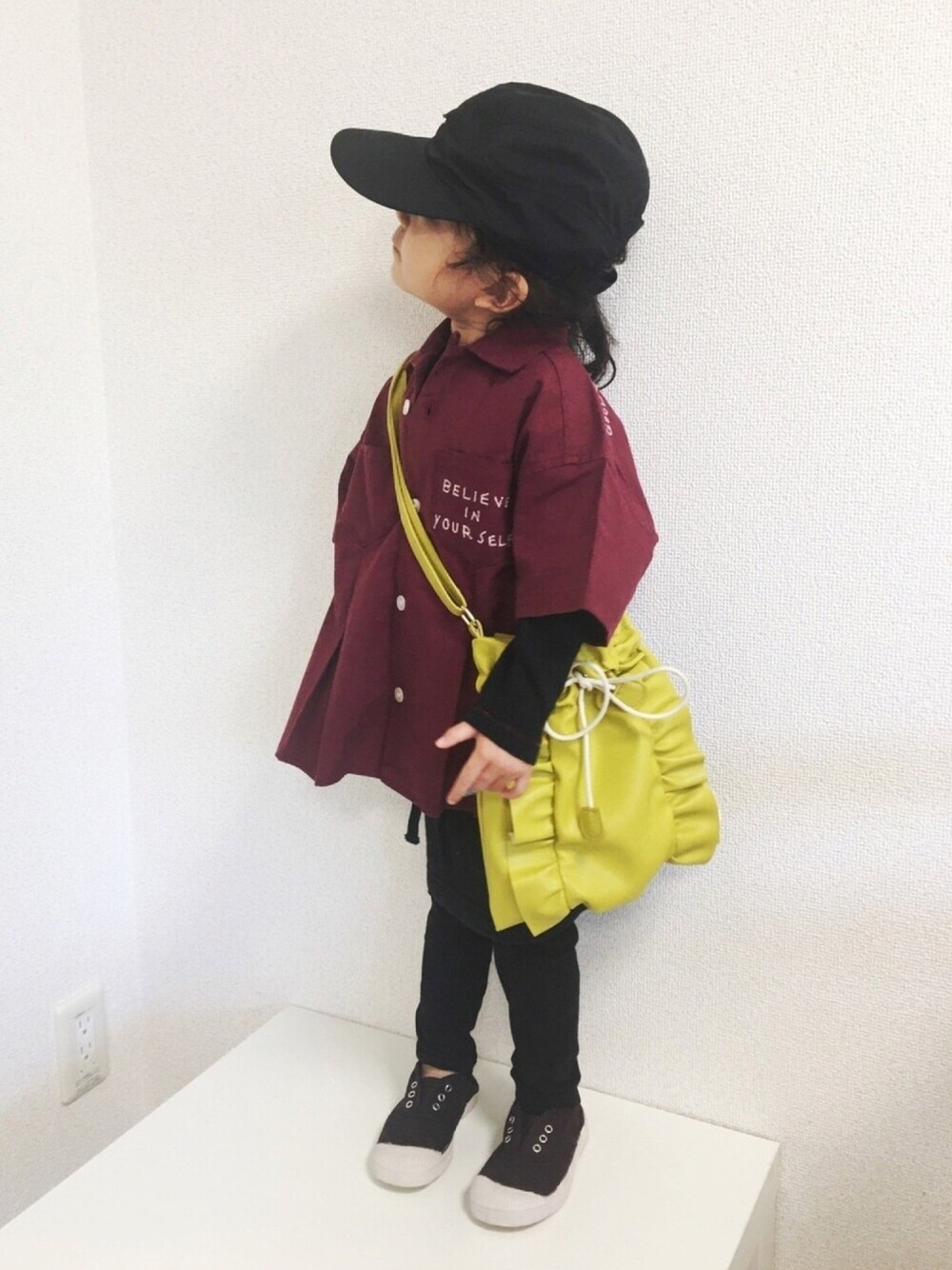 イエロー系のショルダーバッグ、ブラック系のスカート、パープル系のスリッポンを着用したキッズの秋コーディネートの1枚目の写真