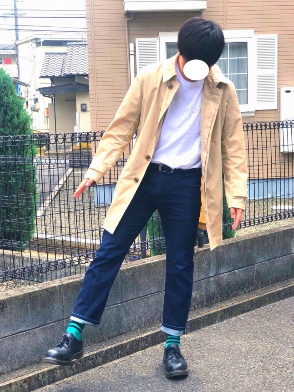 ブラック系のブーツ、ベージュ系のステンカラーコート、ブルー系のデニムパンツを着用したメンズの春コーディネートの1枚目の写真