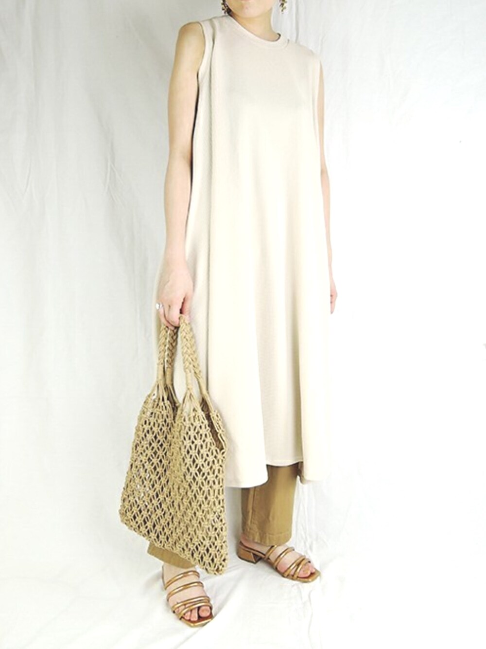 ベージュ系のトートバッグ、ゴールド系のサンダルを着用したレディースの夏コーディネートの1枚目の写真