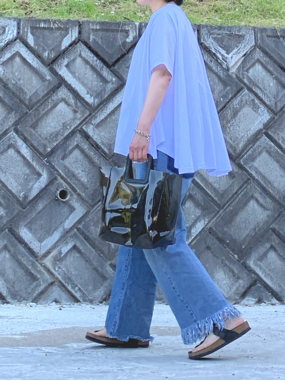 ブラック系のトートバッグ、ホワイト系のTシャツ/カットソー、ブルー系のデニムパンツを着用したレディースの夏コーディネートの1枚目の写真