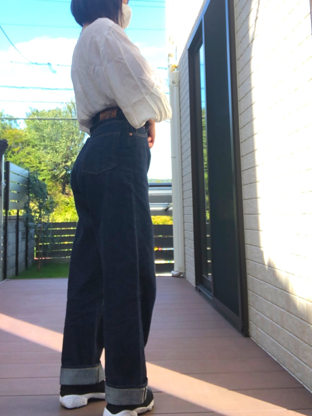 ブルー系のデニムパンツ、ホワイト系のシャツ/ブラウス、ブラック系のスニーカーを着用したレディースの秋コーディネートの1枚目の写真