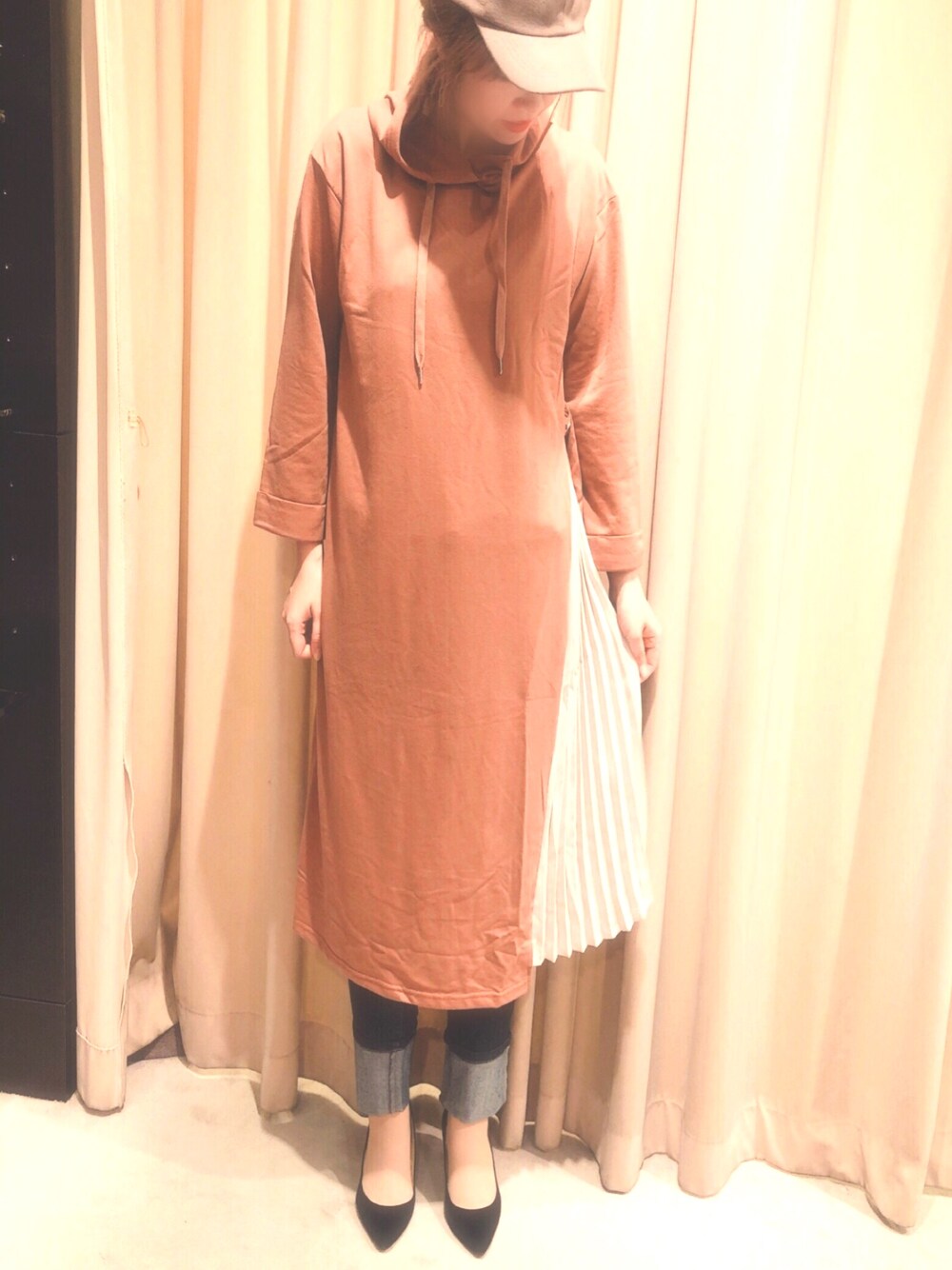 ブラウン系のワンピース、ブルー系のデニムパンツ、ブラウン系のキャップを着用したレディースの秋コーディネートの1枚目の写真