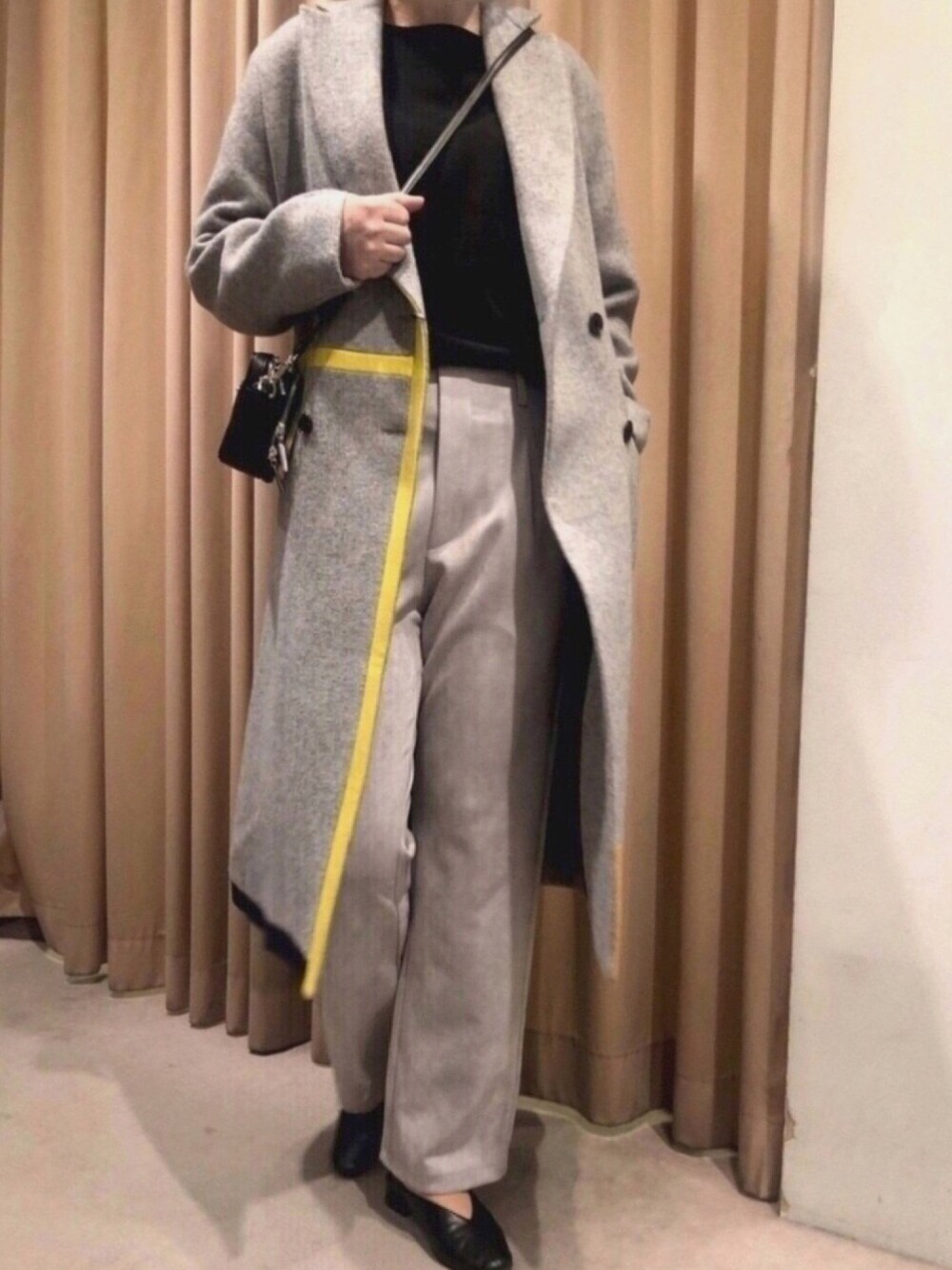 グレー系のチェスターコート、グレー系のその他パンツ、ブラック系のショルダーバッグを着用したレディースの冬コーディネートの1枚目の写真