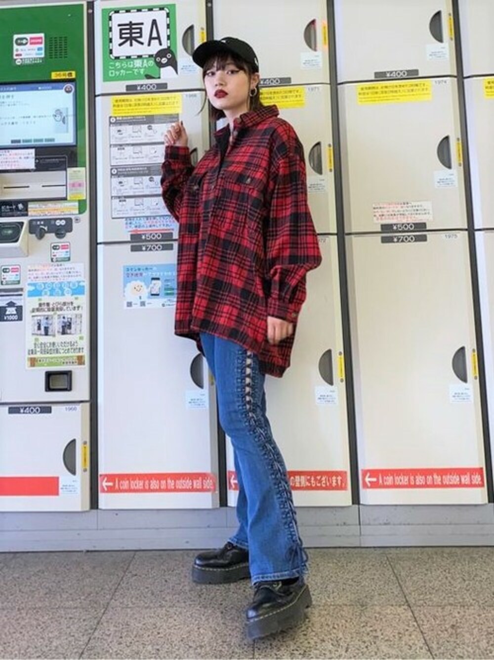 レッド系のミリタリージャケット、ブルー系のデニムパンツ、ブラック系のキャップを着用したレディースの秋コーディネートの1枚目の写真