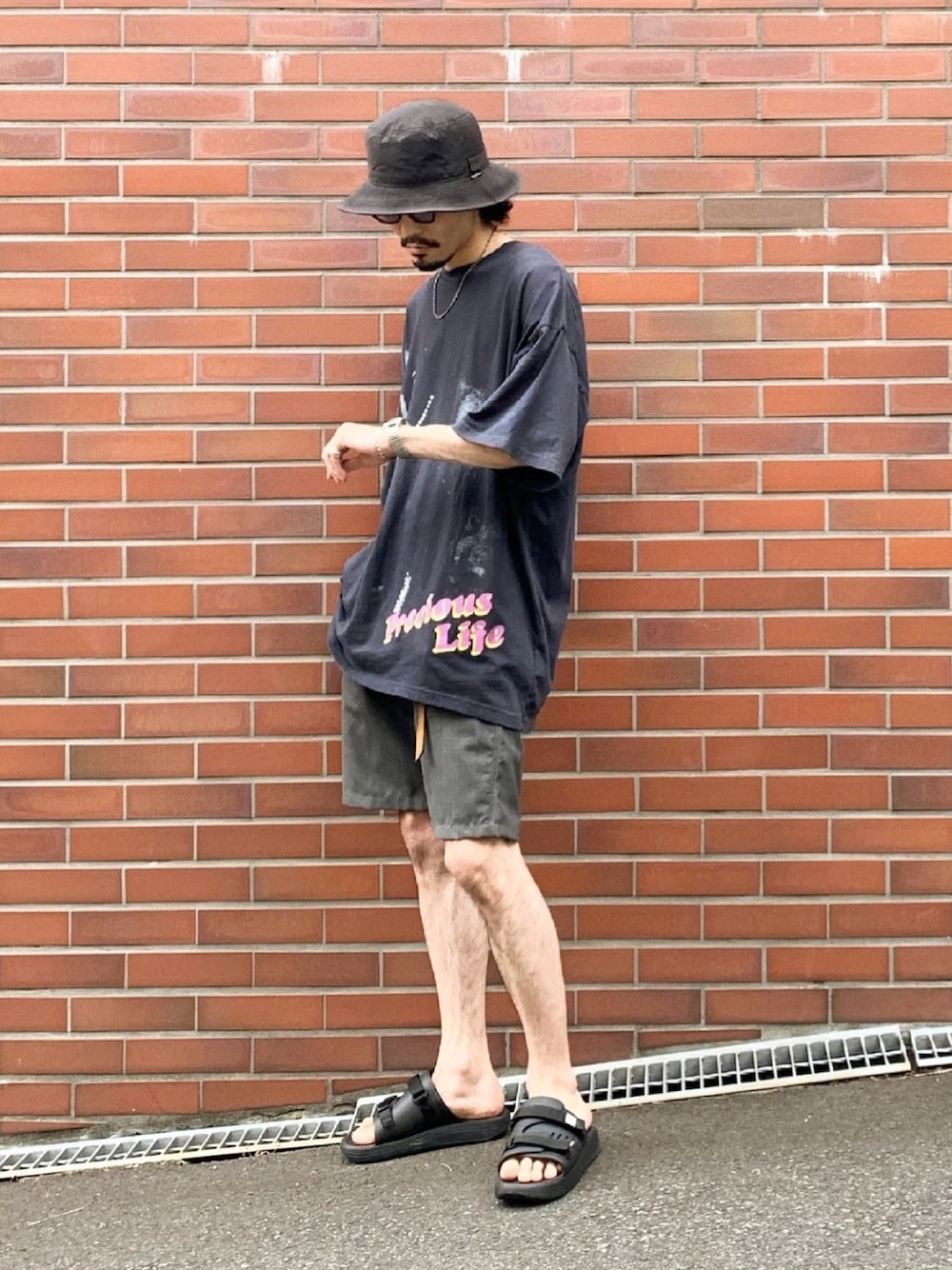 ブラック系のTシャツ/カットソー、グレー系のパンツ、ブラック系のサンダルを着用したメンズの春コーディネートの1枚目の写真