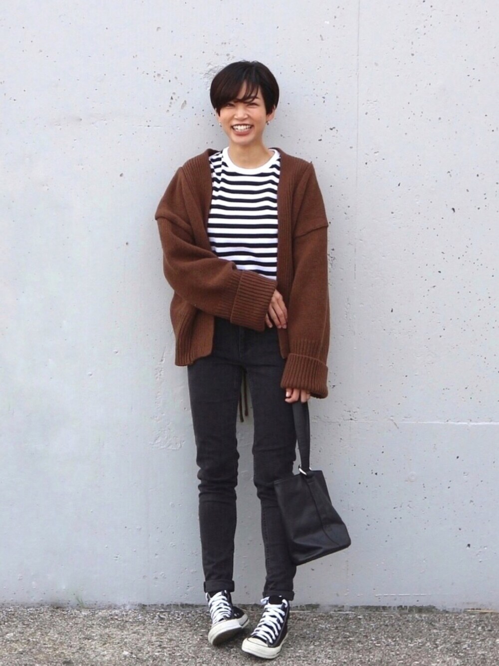 ブラック系のスニーカー、ブラウン系のカーディガン/ボレロ、ホワイト系のTシャツ/カットソーを着用したレディースの冬コーディネートの1枚目の写真