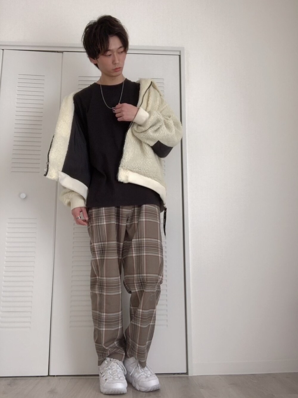 ホワイト系のブルゾン、ブラック系のTシャツ/カットソー、ベージュ系のスラックスを着用したメンズの春コーディネートの1枚目の写真
