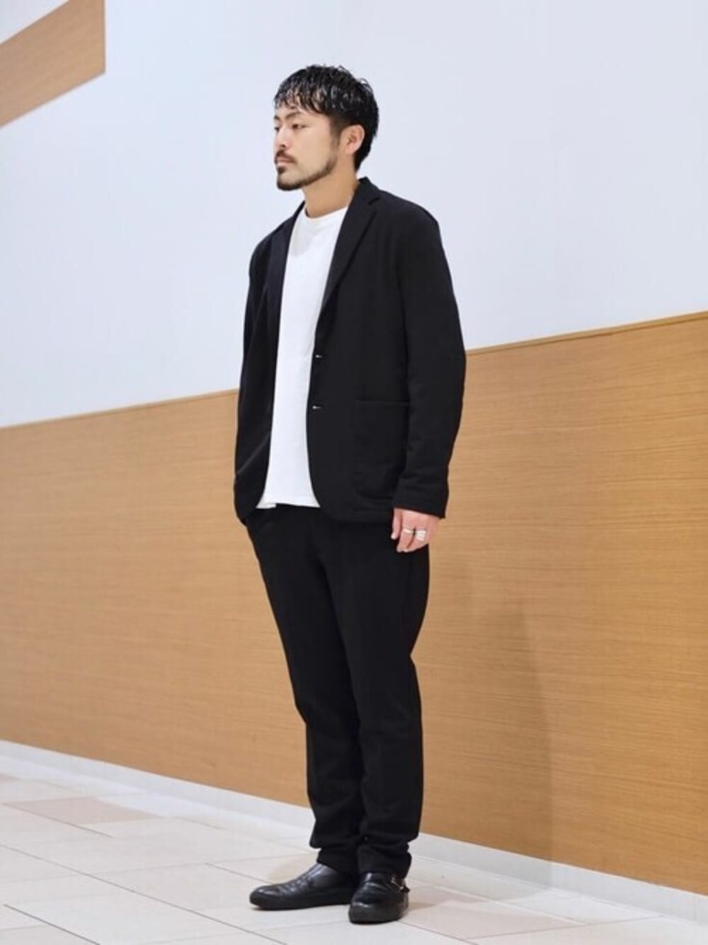 ブラック系のテーラードジャケット、ブラック系のスラックス、ホワイト系のTシャツ/カットソーを着用したメンズの冬コーディネートの1枚目の写真