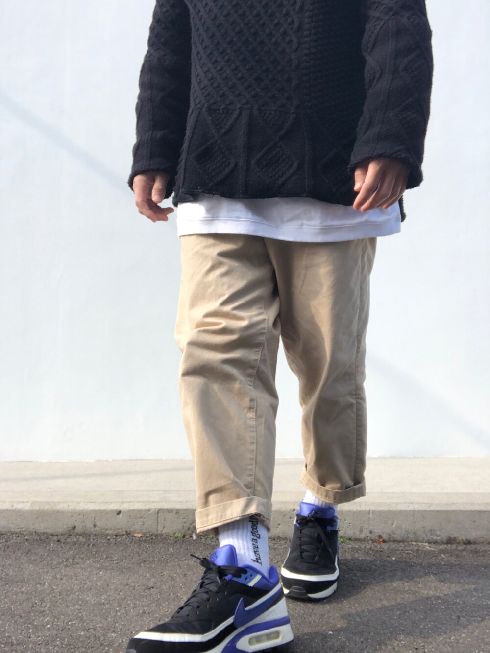 ブラック系のニット/セーター、ホワイト系のTシャツ/カットソー、ベージュ系のチノパンツを着用したメンズの冬コーディネートの1枚目の写真