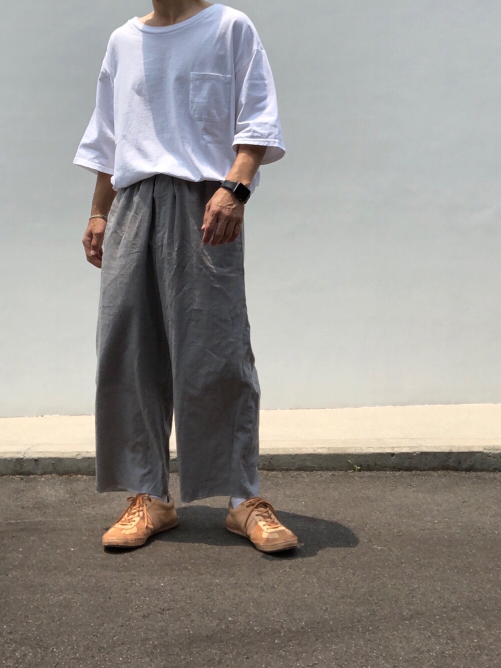 ホワイト系のTシャツ/カットソー、グレー系のパンツ、ベージュ系のシューズを着用したメンズの夏コーディネートの1枚目の写真