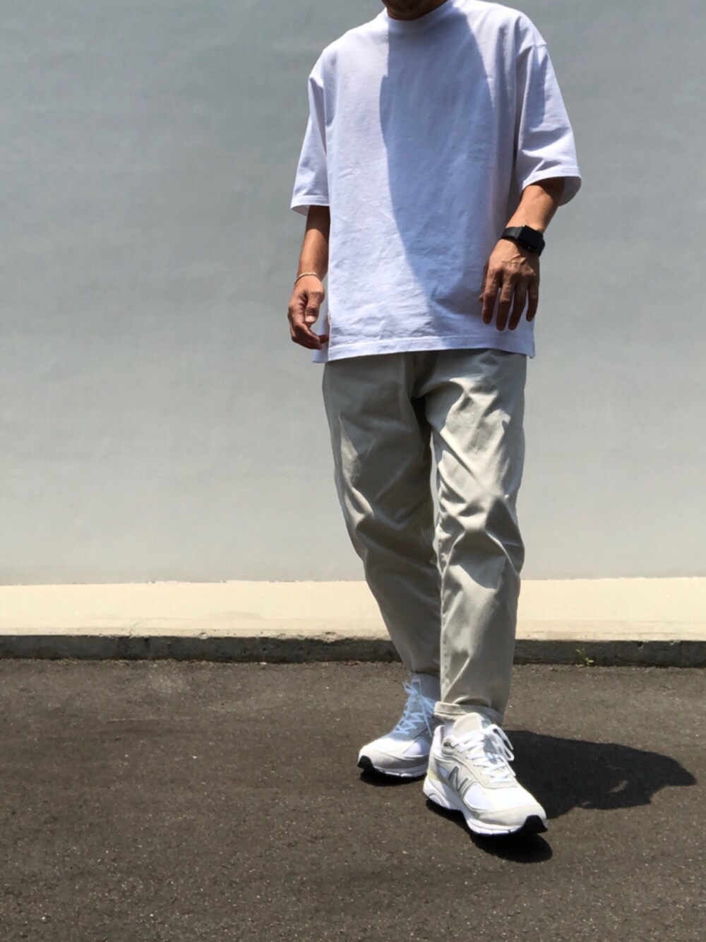 ホワイト系のTシャツ/カットソー、ベージュ系のチノパンツ、ホワイト系のスニーカーを着用したメンズの夏コーディネートの1枚目の写真