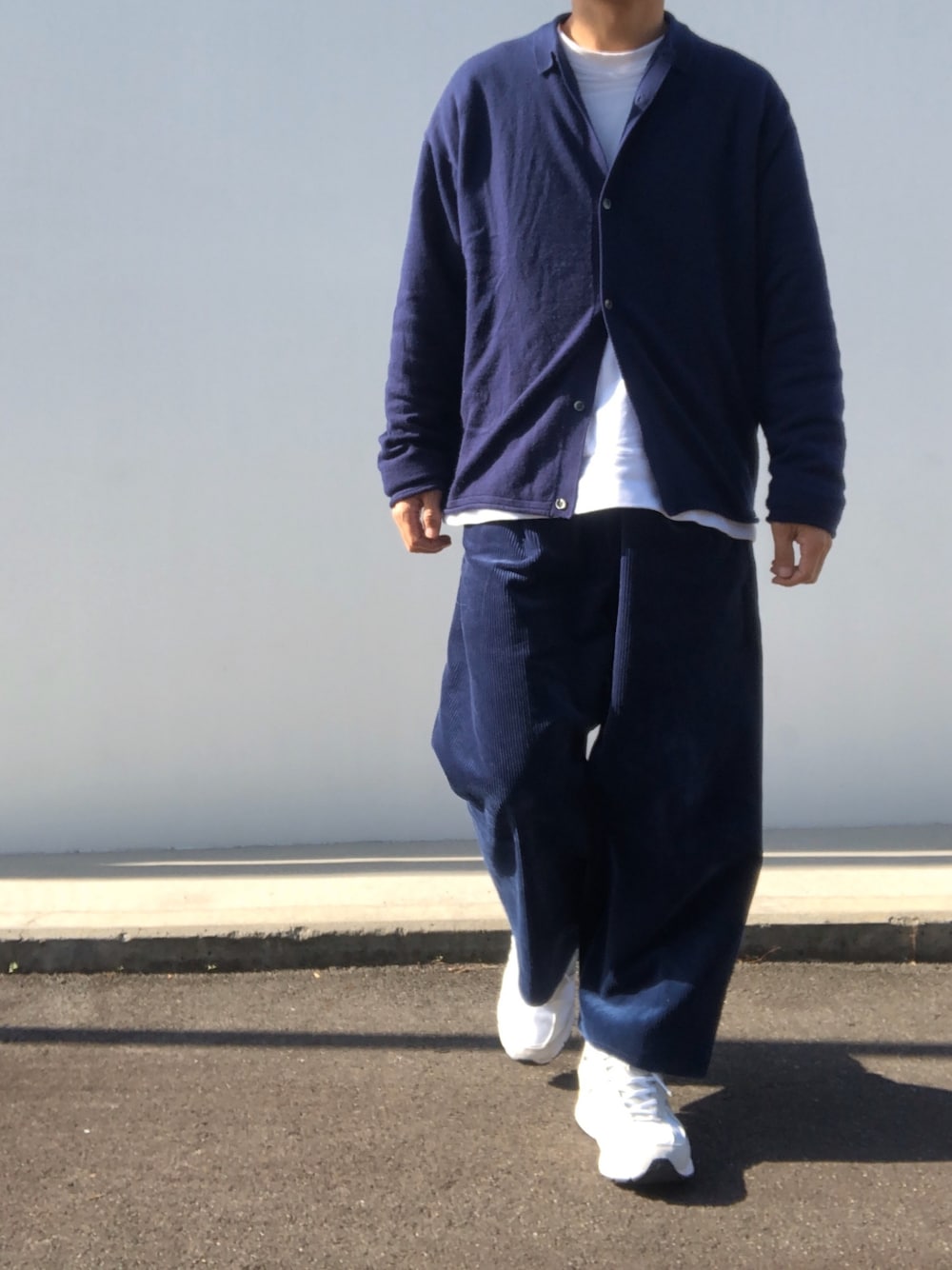 ホワイト系のスウェット、ブルー系のニット/セーター、ブルー系のパンツを着用したメンズの秋コーディネートの1枚目の写真