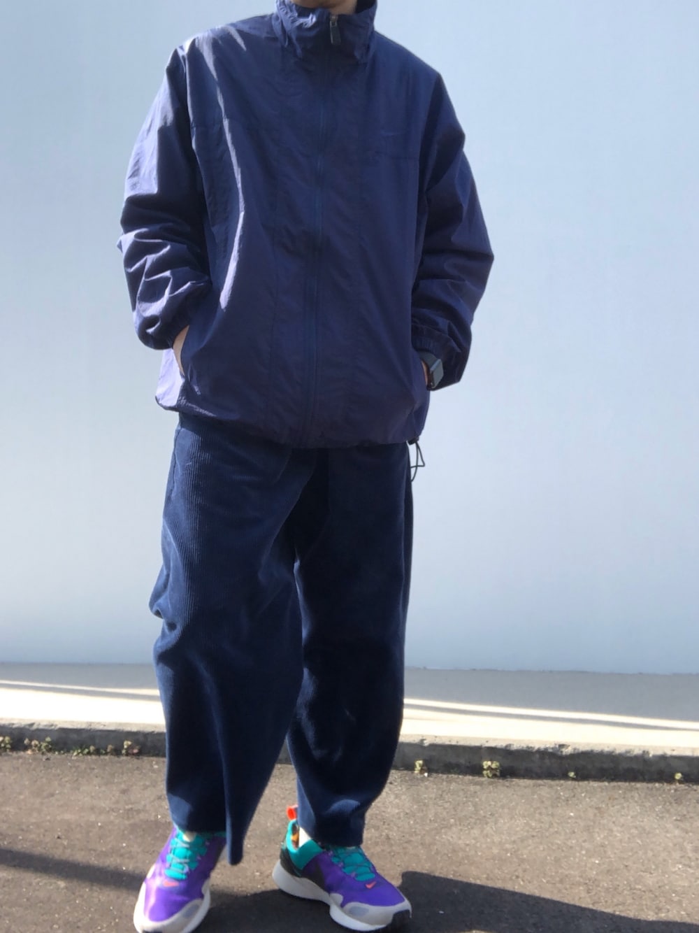 ブルー系のナイロンジャケット、ブルー系のパンツ、パープル系のスニーカーを着用したメンズの冬コーディネートの1枚目の写真