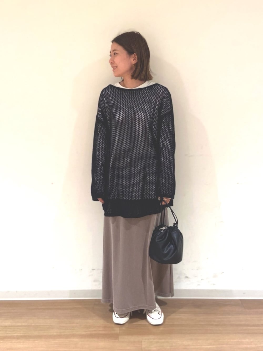 ブラック系のニット/セーター、ホワイト系のTシャツ/カットソー、ブラウン系のスカートを着用したレディースの冬コーディネートの1枚目の写真