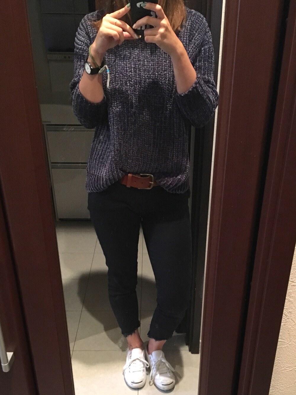 ブラック系のデニムパンツ、ブルー系のニット/セーター、ホワイト系のスニーカーを着用したレディースの秋コーディネートの1枚目の写真