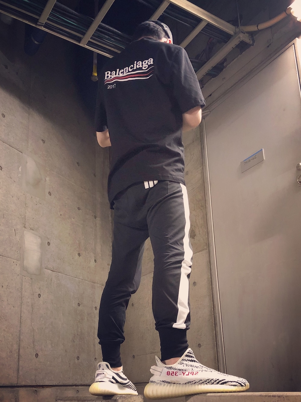 ブラック系のTシャツ/カットソー、ブラック系のその他パンツ、ホワイト系のスニーカーを着用したメンズの秋コーディネートの1枚目の写真