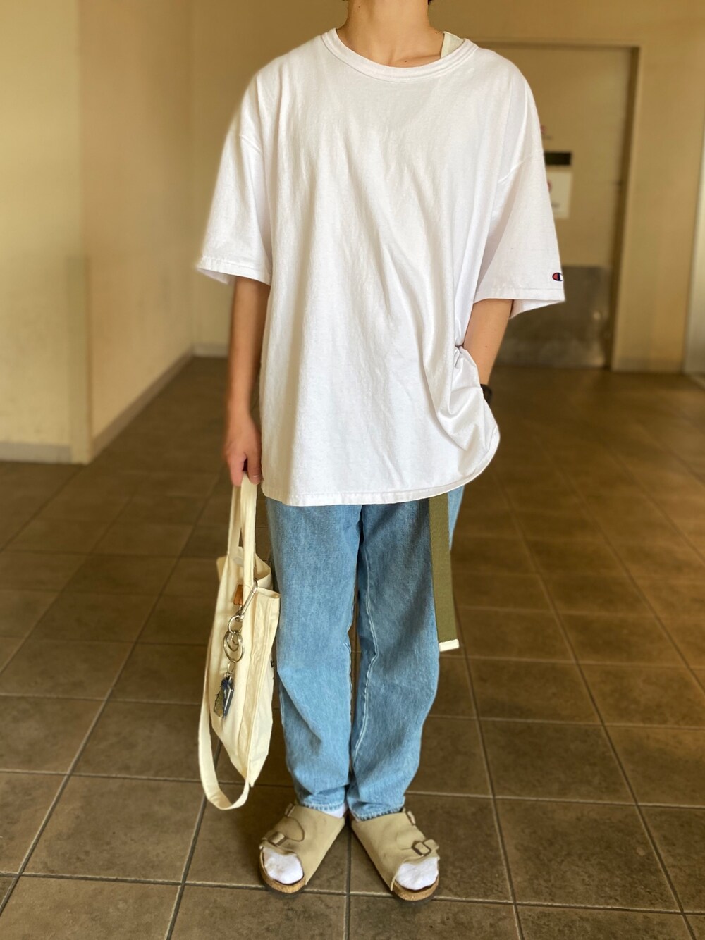 ホワイト系のTシャツ/カットソー、ブルー系のデニムパンツ、ベージュ系のサンダルを着用したメンズの夏コーディネートの1枚目の写真