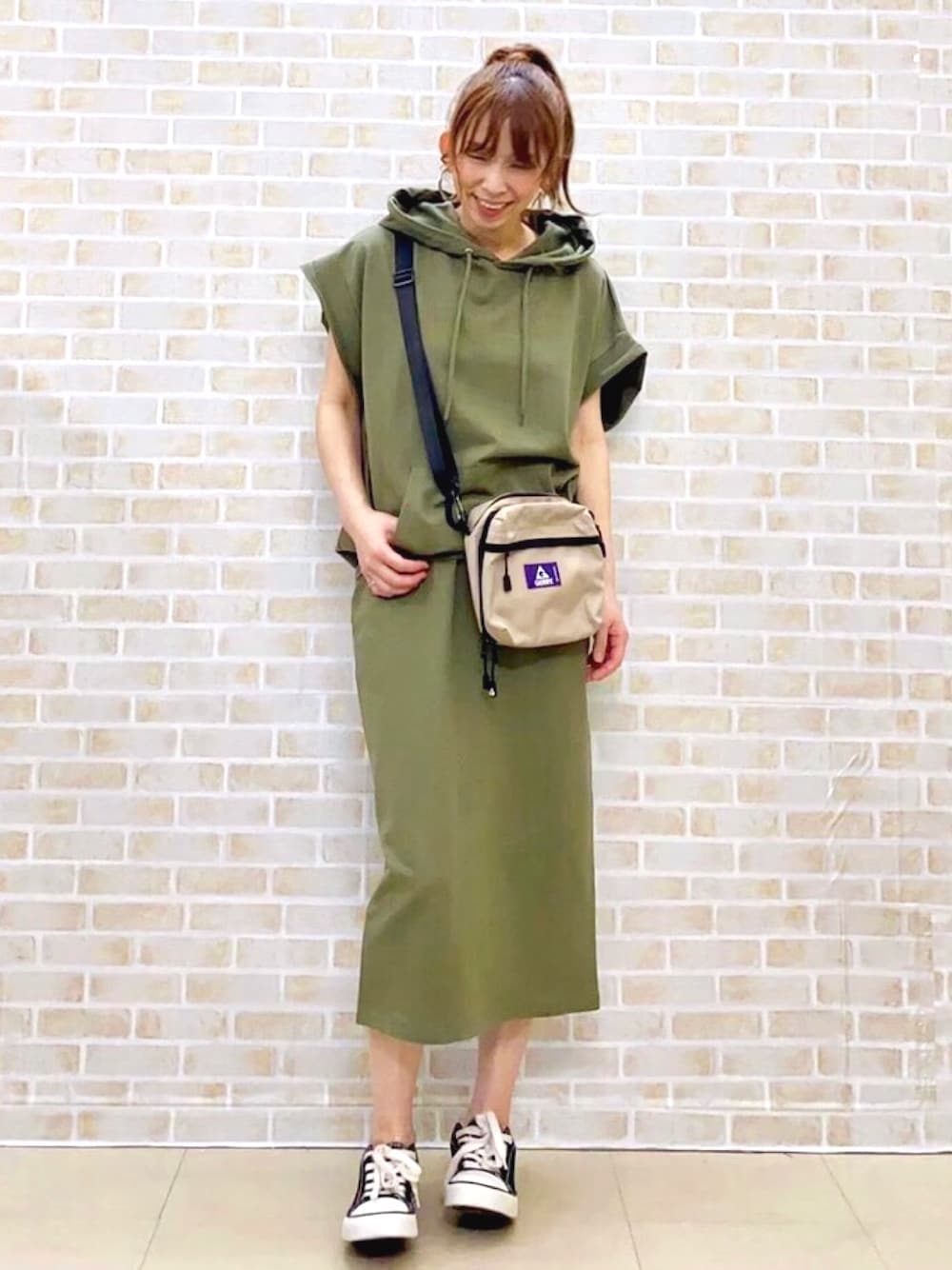 グリーン系のパーカー、グリーン系のスカート、ベージュ系のショルダーバッグを着用したレディースの夏コーディネートの1枚目の写真