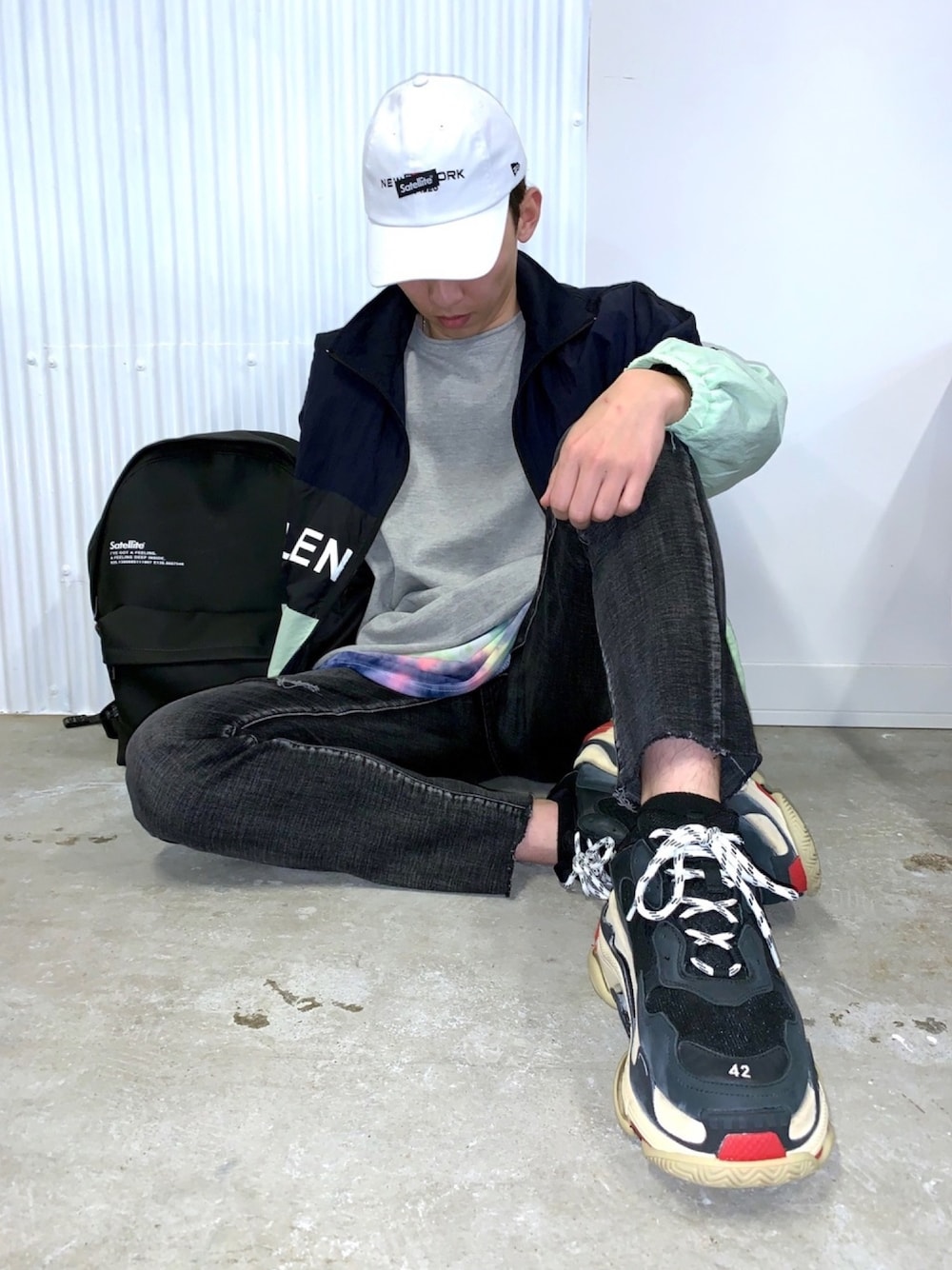 グレー系のTシャツ/カットソー、ブラック系のバックパック/リュック、ブルー系のスニーカーを着用したメンズの春コーディネートの1枚目の写真