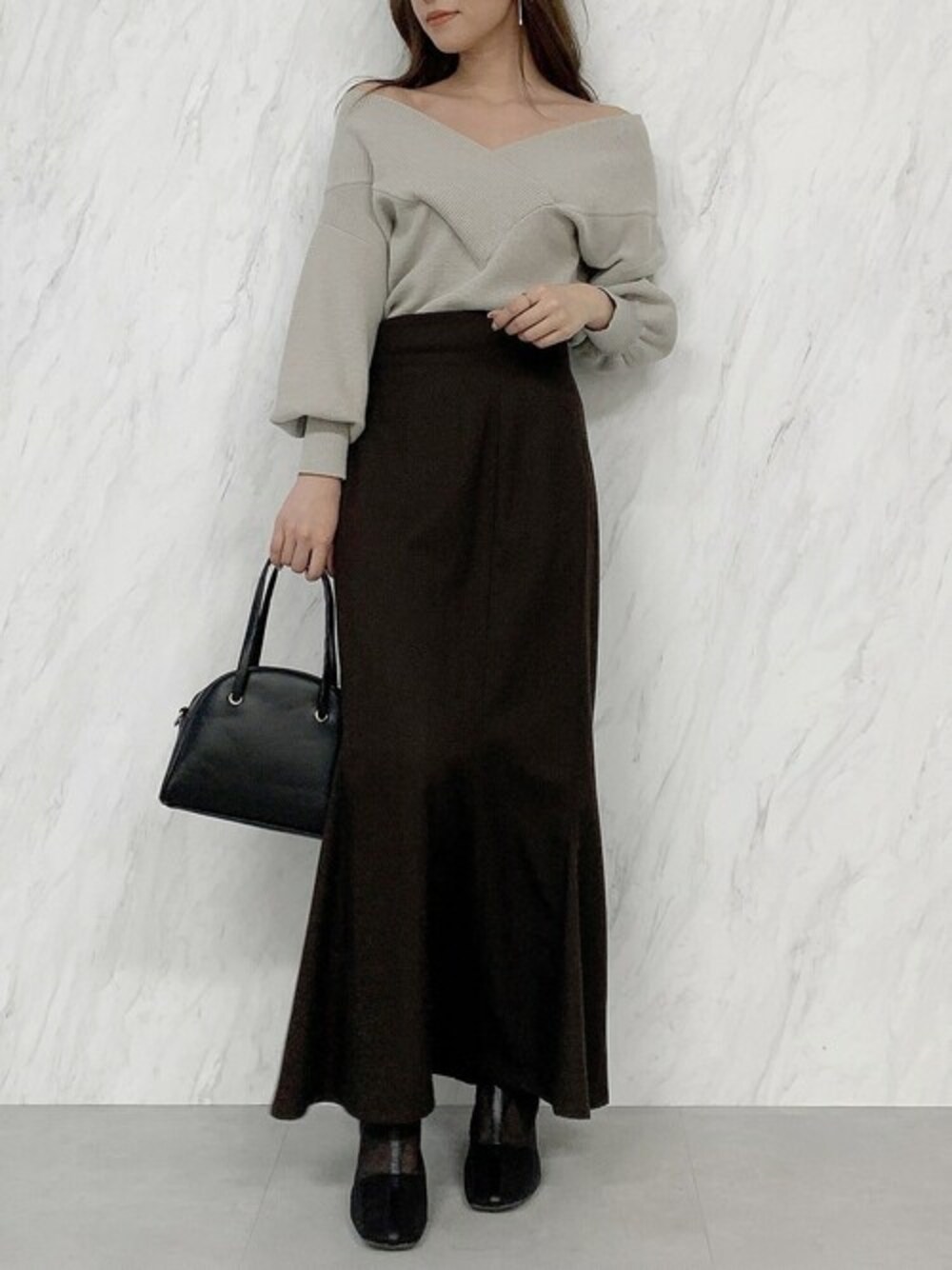 グレー系のニット/セーター、ブラウン系のスカート、ブラック系のブーツを着用したレディースの冬コーディネートの1枚目の写真