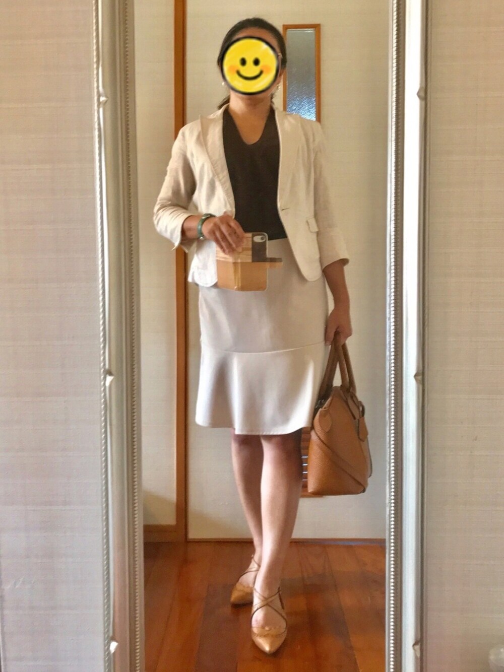 ベージュ系のスカート、ベージュ系のパンプス、ブラウン系のハンドバッグを着用したレディースの夏コーディネートの1枚目の写真