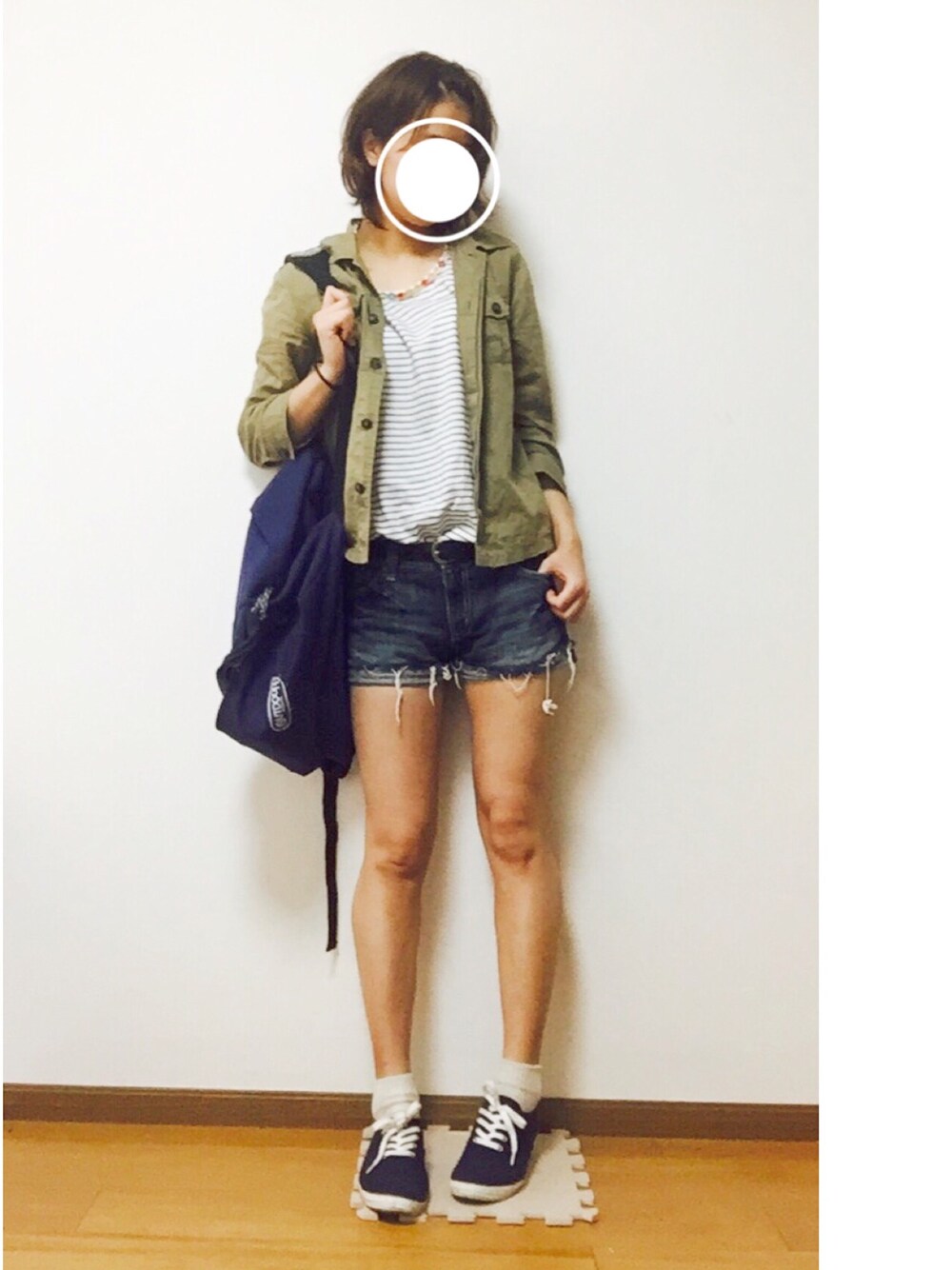 ホワイト系のタンクトップ、グリーン系のトップス、ブルー系のシューズを着用したレディースの春コーディネートの1枚目の写真