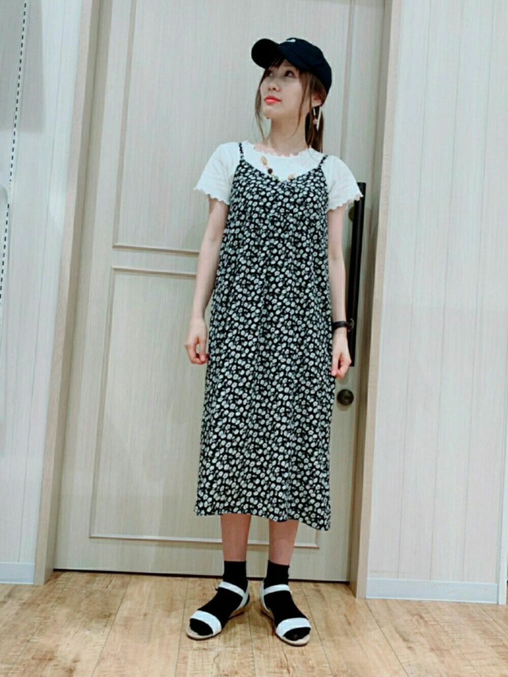 ホワイト系のサンダル、ブラック系のワンピース、ブラック系のキャップを着用したレディースの夏コーディネートの1枚目の写真