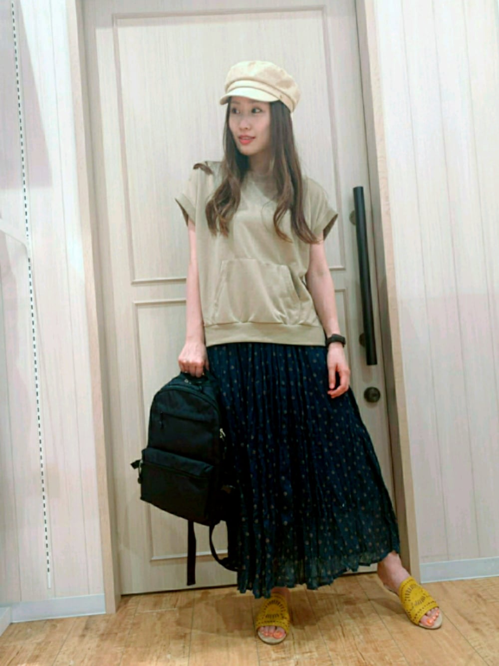 グリーン系のスカート、ベージュ系のTシャツ/カットソー、ブラック系のバックパック/リュックを着用したレディースの夏コーディネートの1枚目の写真