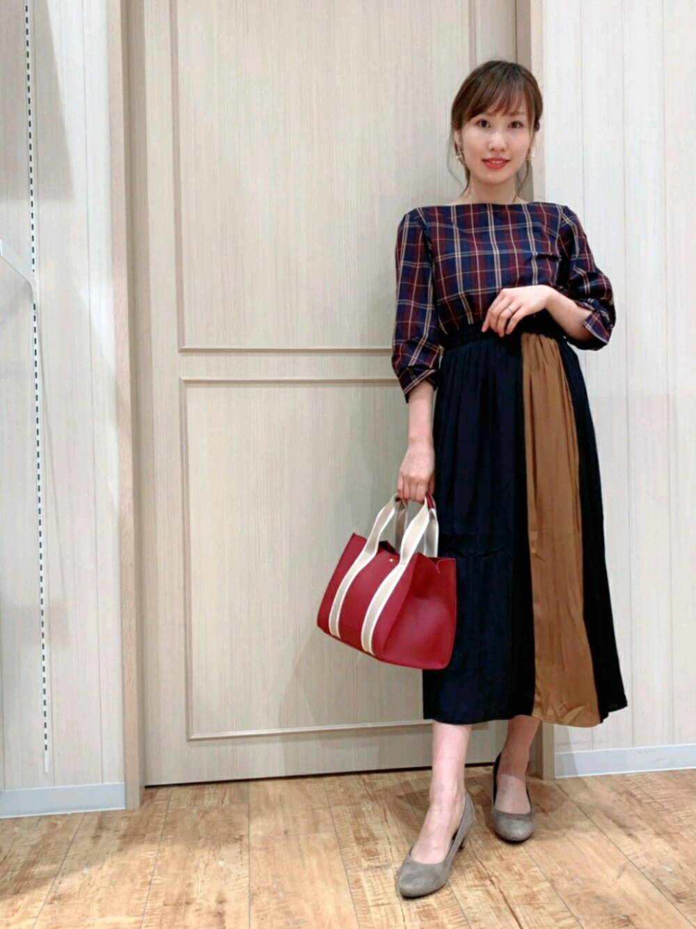 レッド系のトートバッグ、レッド系のトップス、ブルー系のスカートを着用したレディースの夏コーディネートの1枚目の写真
