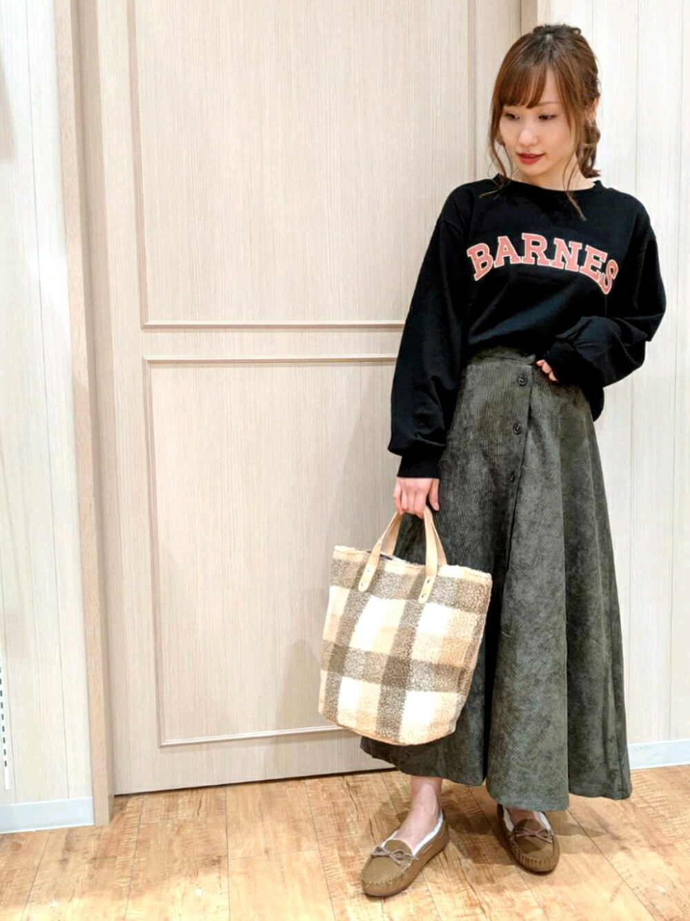 イエロー系のトートバッグ、ブラック系のスウェット、グリーン系のスカートを着用したレディースの秋コーディネートの1枚目の写真