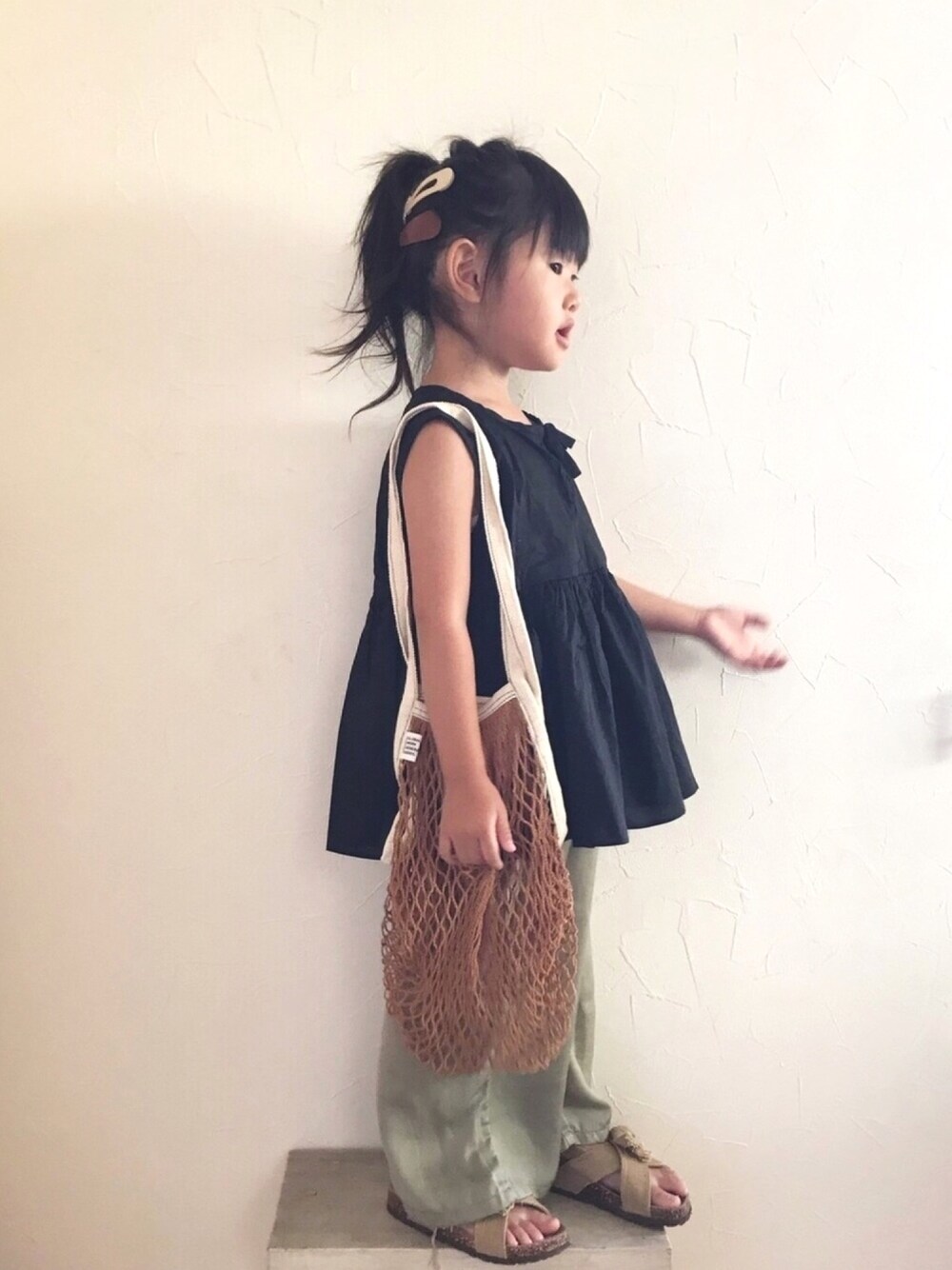 ブラウン系のトートバッグ、グリーン系のその他パンツ、ベージュ系のサンダルを着用したキッズの秋コーディネートの1枚目の写真