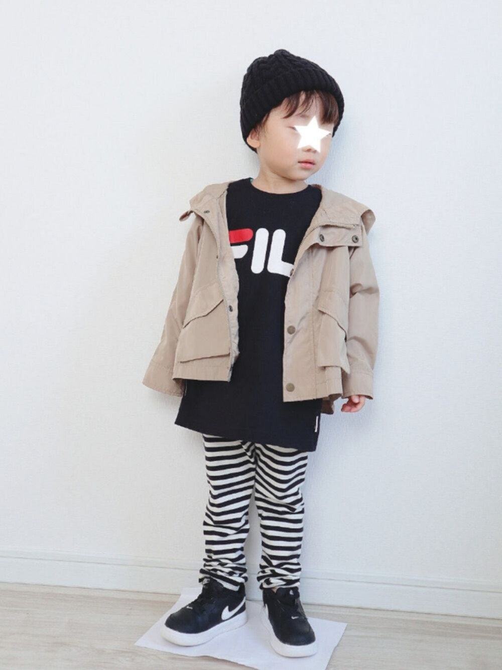 ベージュ系のマウンテンパーカー、ブラック系のTシャツ/カットソー、ブラック系のスニーカーを着用したキッズの秋コーディネートの1枚目の写真