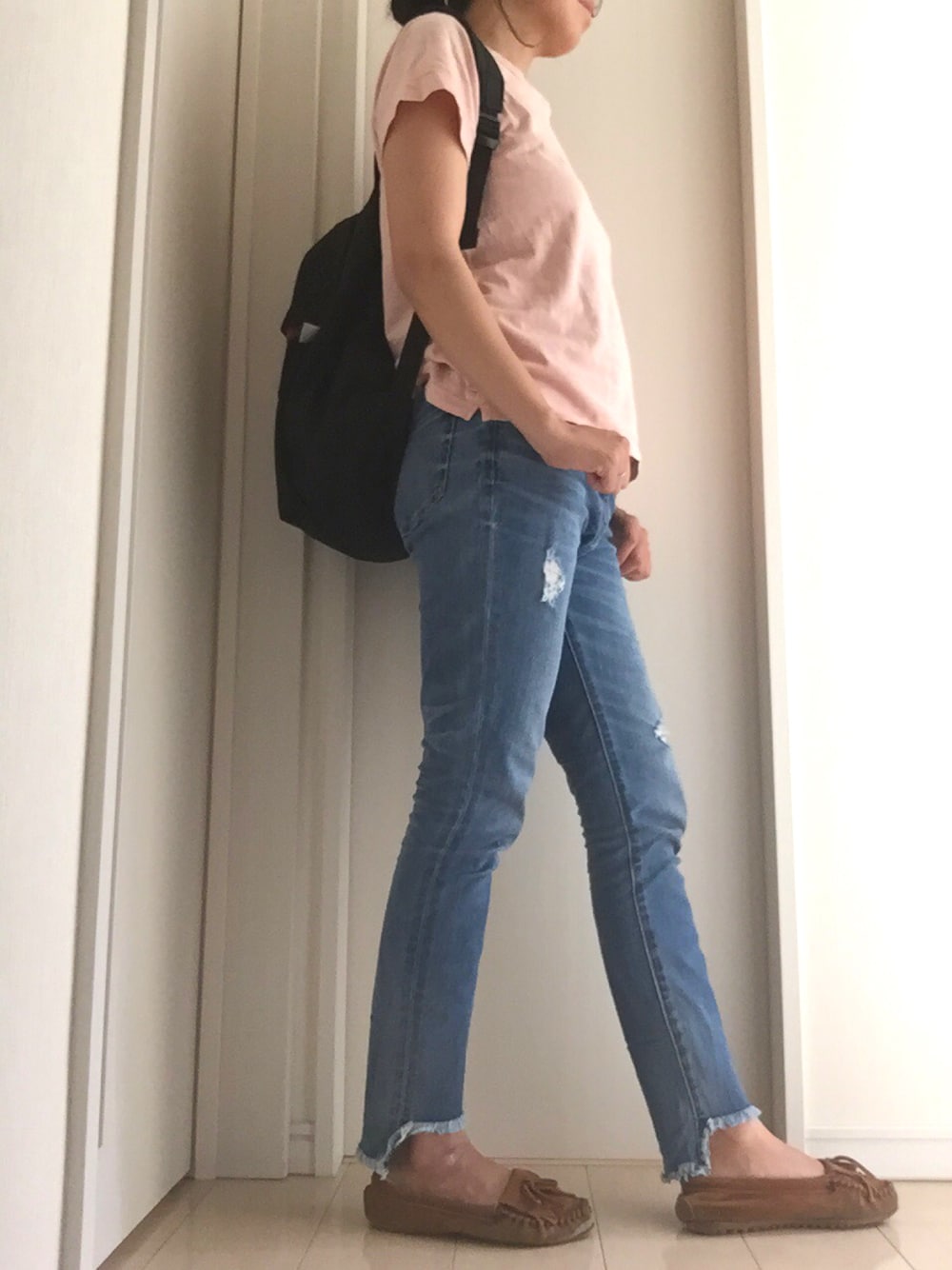 ピンク系のTシャツ/カットソー、ブラック系のバックパック/リュック、ブラウン系のモカシン/デッキシューズを着用したレディースの春コーディネートの1枚目の写真