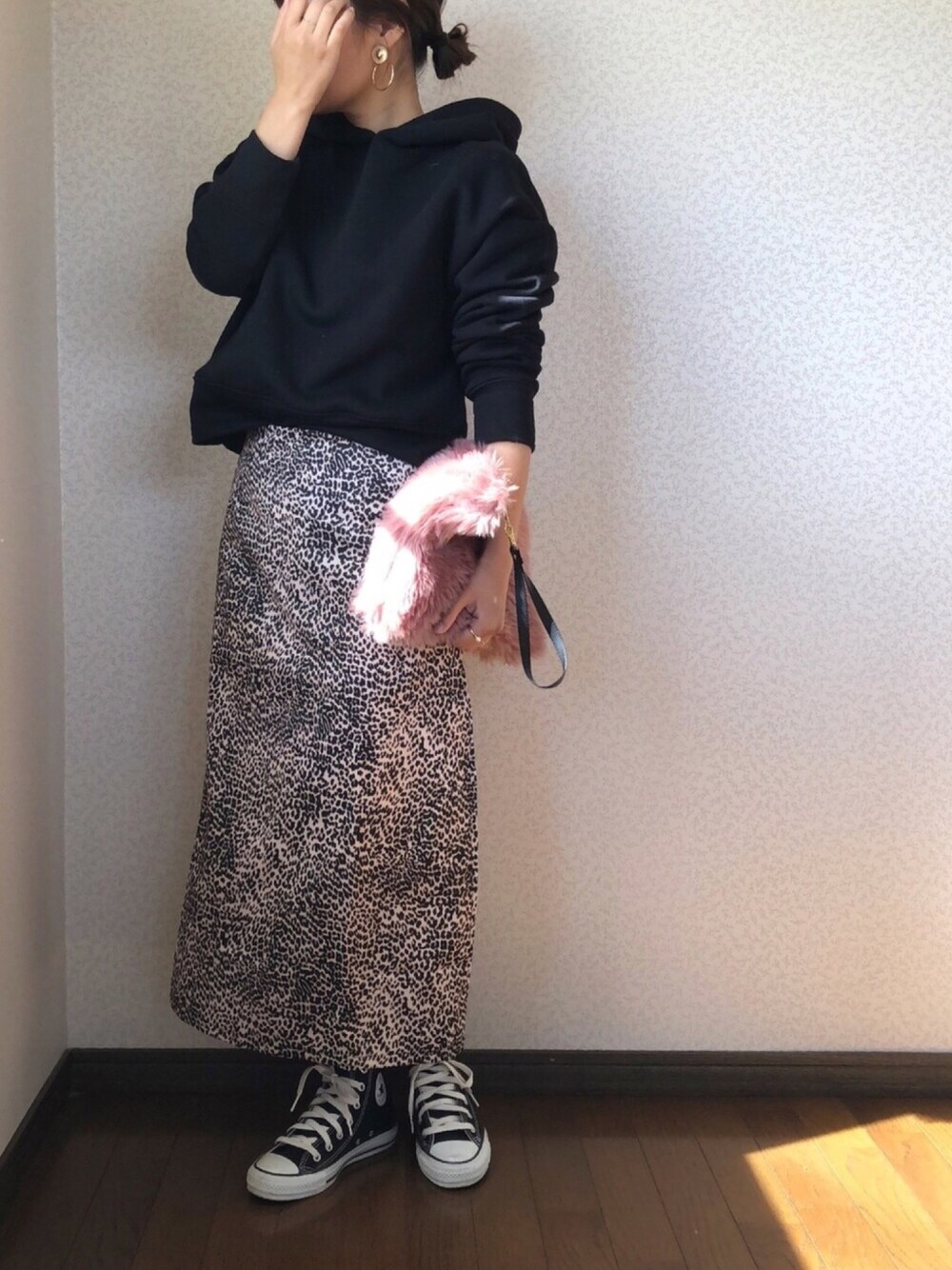 ブラック系のパーカー、ピンク系のクラッチバッグ、ブラック系のスニーカーを着用したレディースの秋コーディネートの1枚目の写真