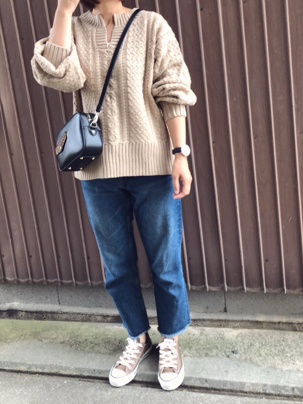 ベージュ系のニット/セーター、ブラック系のショルダーバッグ、ブルー系のデニムパンツを着用したレディースの秋コーディネートの1枚目の写真