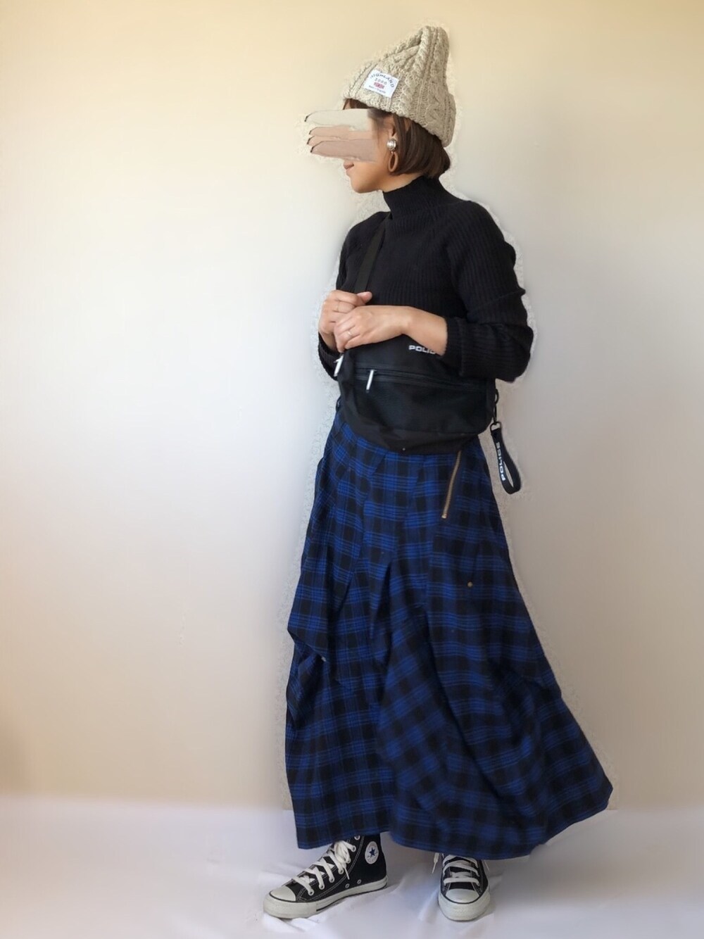 ブラック系のニット/セーター、ブルー系のスカート、ブラック系のスニーカーを着用したレディースの秋コーディネートの1枚目の写真