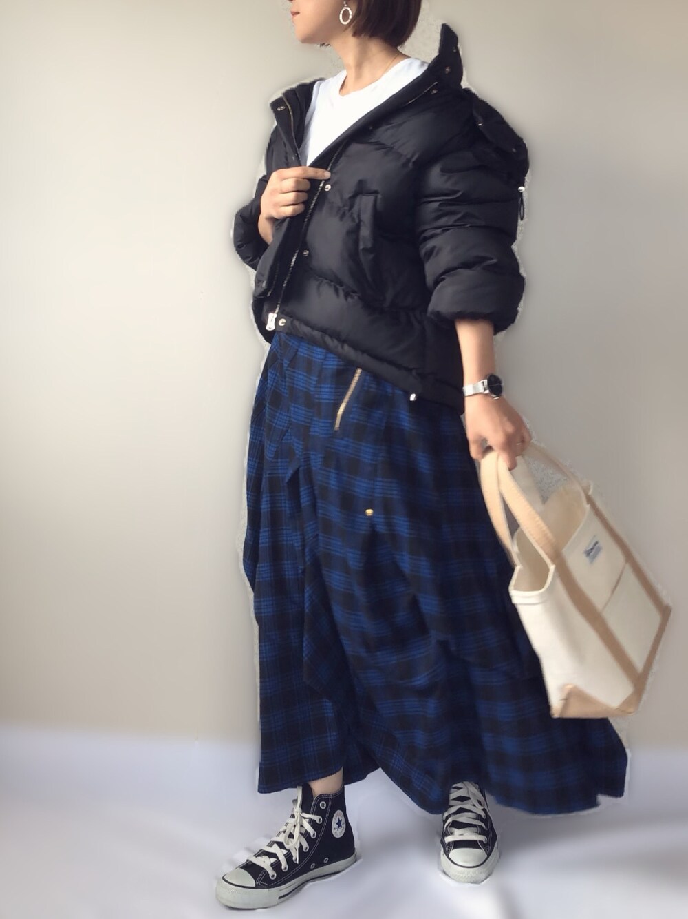 ブラック系のダウンジャケット/コート、ブルー系のスカート、ベージュ系のトートバッグを着用したレディースの秋コーディネートの1枚目の写真
