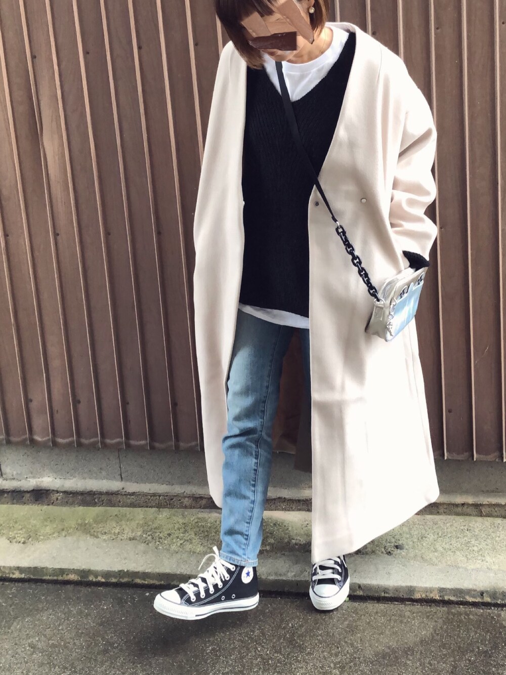 ベージュ系のノーカラーコート、ブラック系のニット/セーター、ベージュ系のショルダーバッグを着用したレディースの冬コーディネートの1枚目の写真