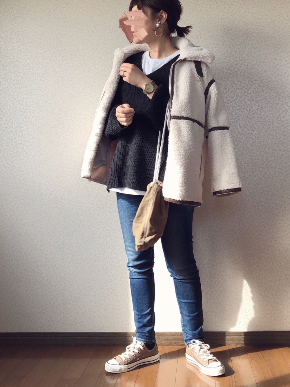 ベージュ系のブルゾン、ブラック系のニット/セーター、ベージュ系のハンドバッグを着用したレディースの冬コーディネートの1枚目の写真