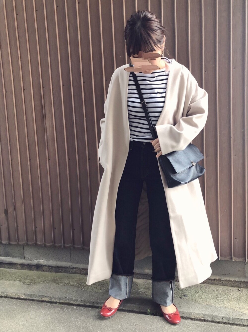 ベージュ系のノーカラーコート、ブルー系のデニムパンツ、ブラック系のショルダーバッグを着用したレディースの冬コーディネートの1枚目の写真