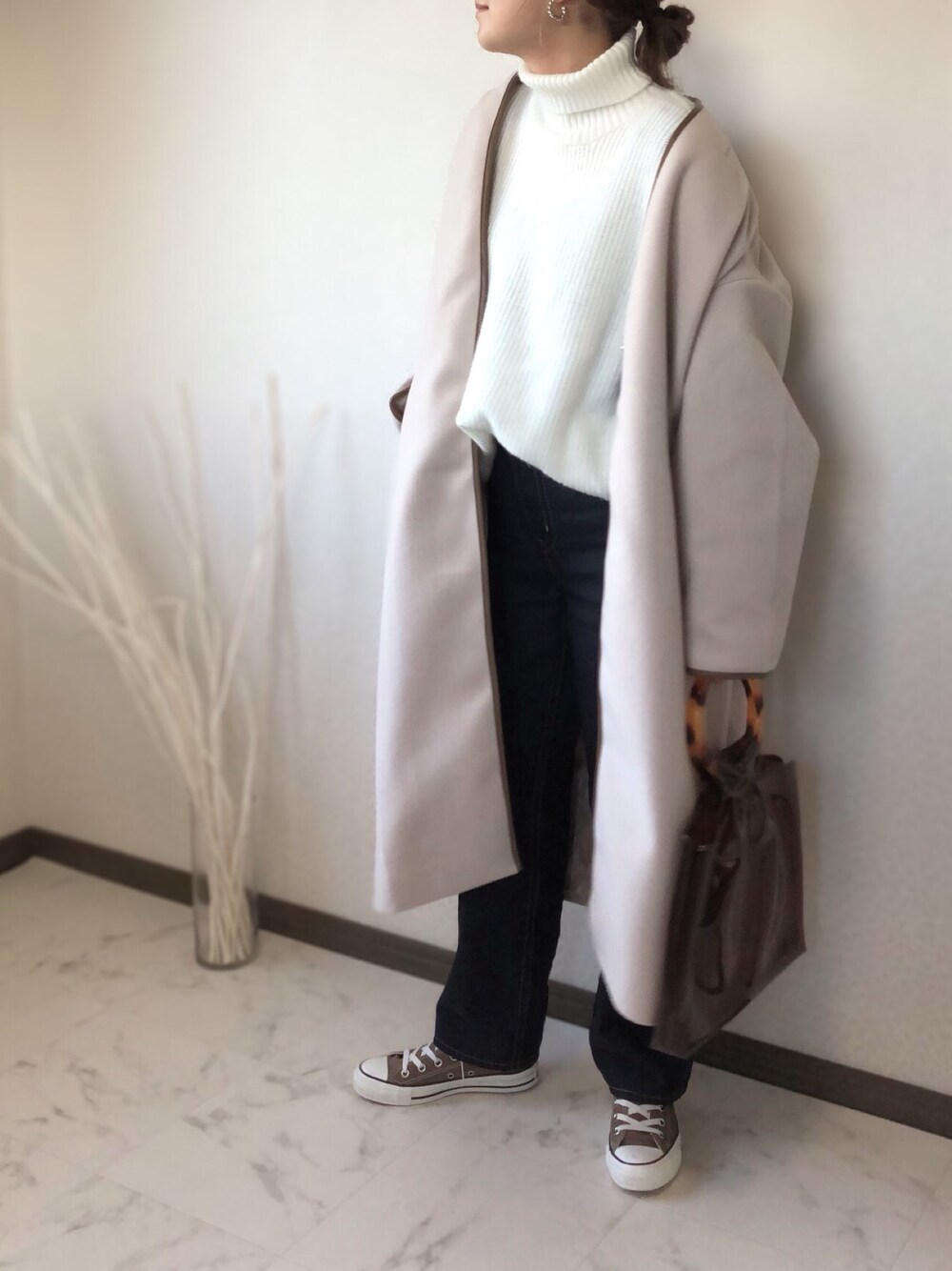 ベージュ系のノーカラーコート、ホワイト系のニット/セーター、ブルー系のデニムパンツを着用したレディースの秋コーディネートの1枚目の写真