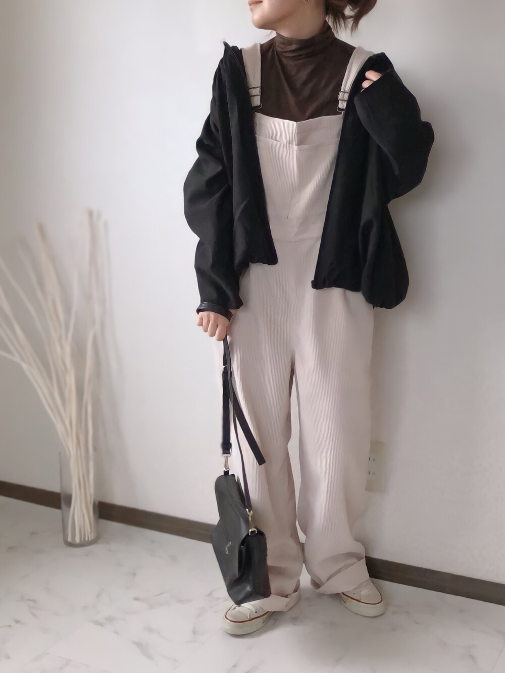 ブラック系のショルダーバッグ、ベージュ系のサロペット/オーバーオール、ホワイト系のスニーカーを着用したレディースの冬コーディネートの1枚目の写真