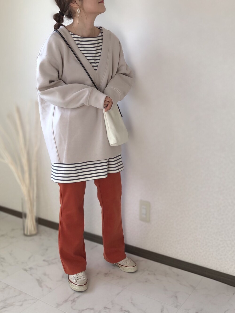 オレンジ系のスラックス、ベージュ系のTシャツ/カットソー、ベージュ系のショルダーバッグを着用したレディースの冬コーディネートの1枚目の写真