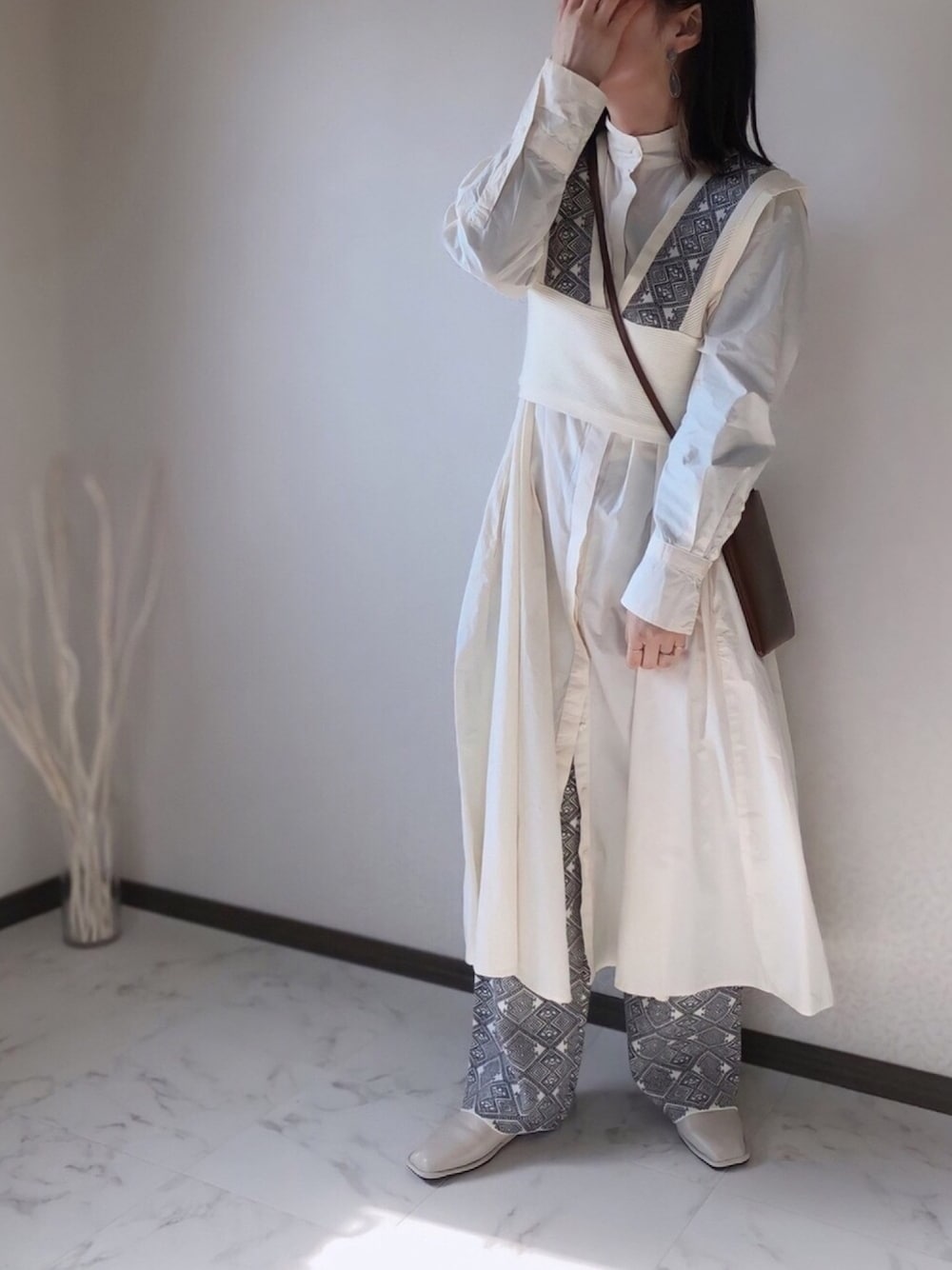 ベージュ系のベスト、ベージュ系のその他パンツ、ホワイト系のワンピースを着用したレディースの冬コーディネートの1枚目の写真