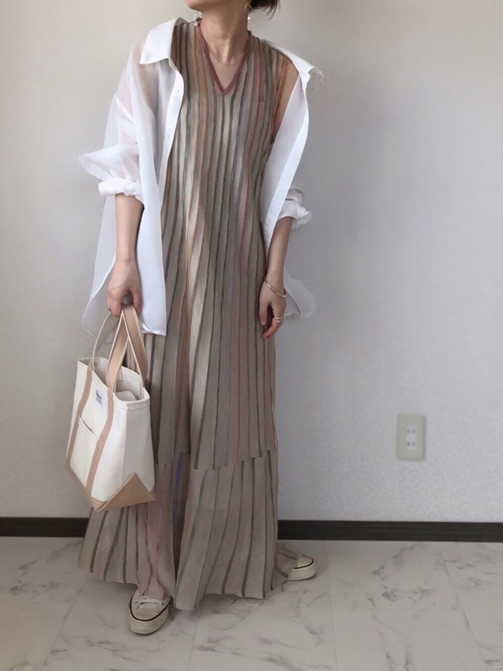 ベージュ系のワンピース、ホワイト系のシャツ/ブラウス、ベージュ系のトートバッグを着用したレディースの春コーディネートの1枚目の写真